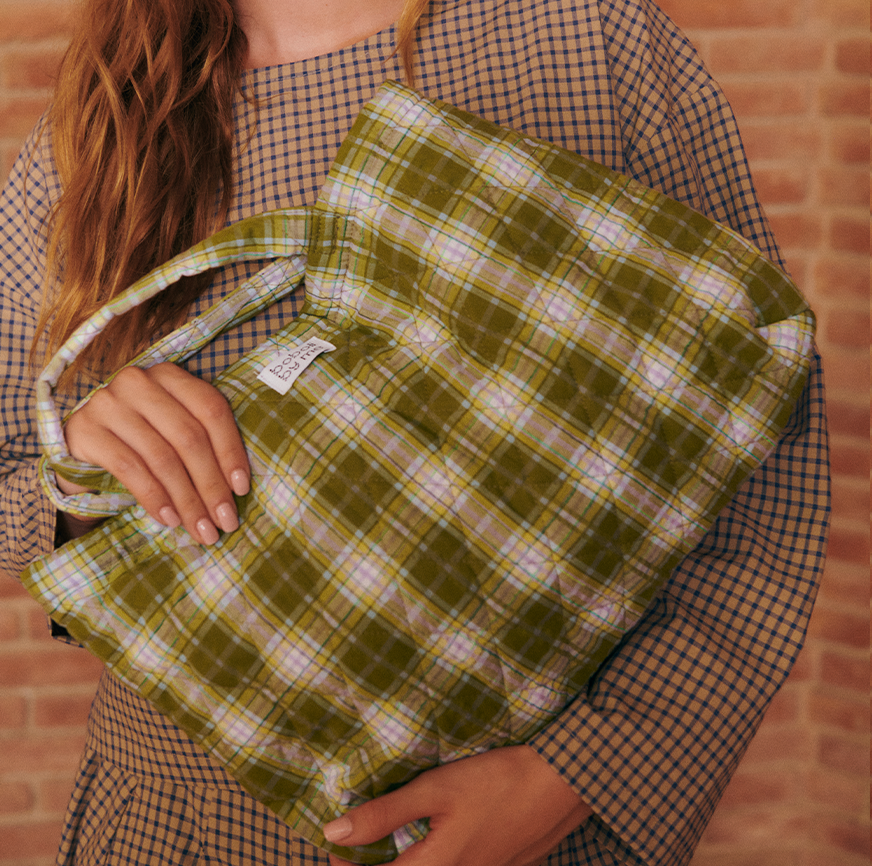 Mujer con bolso acolchado de cuadros verdes, hecho con el kit para accesorios para mejorar la técnica de Boboli by Me.